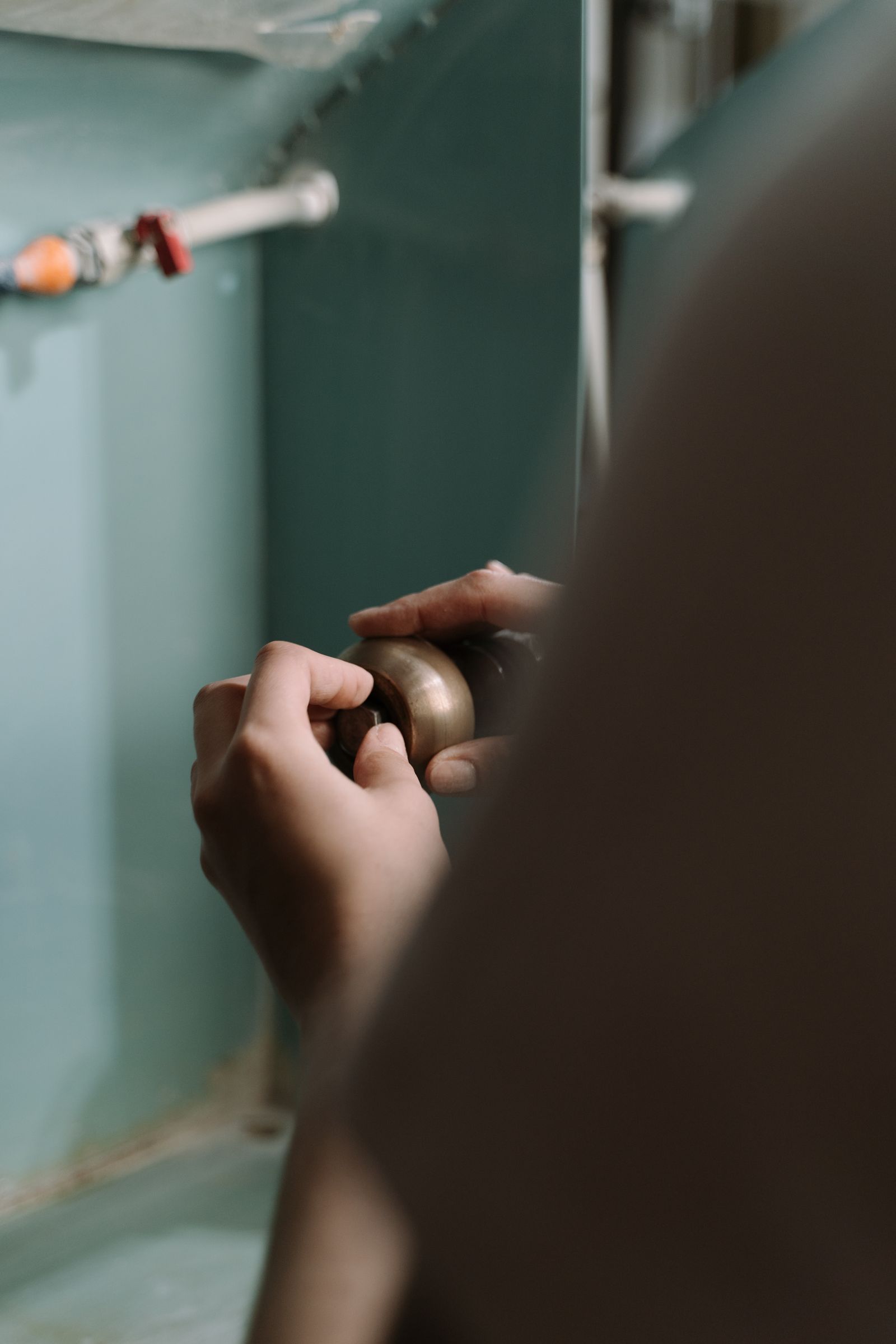 Plumber's hands adjusting a pipe fitting under a kitchen sink